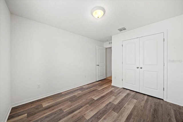 unfurnished bedroom with dark hardwood / wood-style floors and a closet