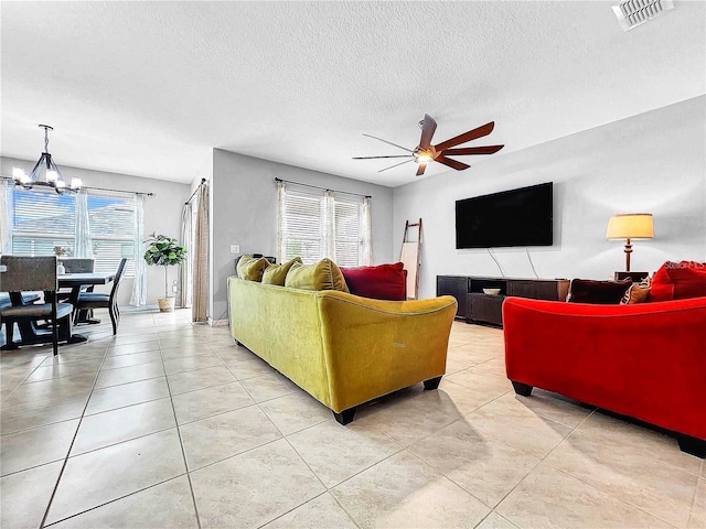 tiled living room featuring ceiling fan with notable chandelier and a textured ceiling