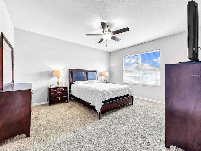 bedroom with ceiling fan, light colored carpet, and a textured ceiling