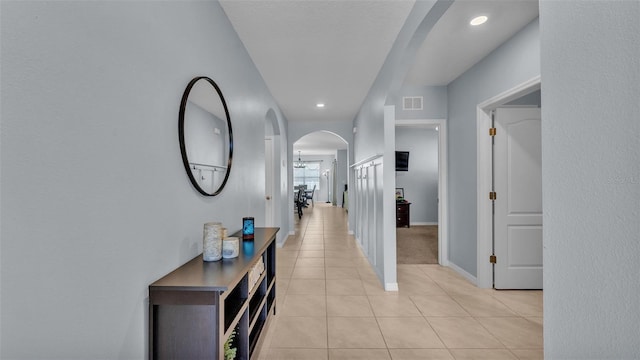 corridor featuring visible vents, arched walkways, baseboards, an inviting chandelier, and light tile patterned flooring