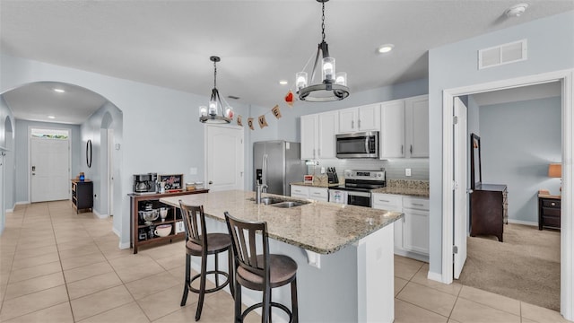 kitchen featuring light tile patterned floors, visible vents, arched walkways, appliances with stainless steel finishes, and a sink