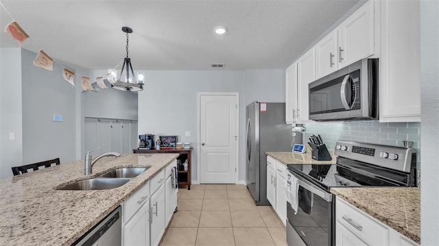 kitchen with light tile patterned floors, a sink, white cabinets, appliances with stainless steel finishes, and decorative backsplash