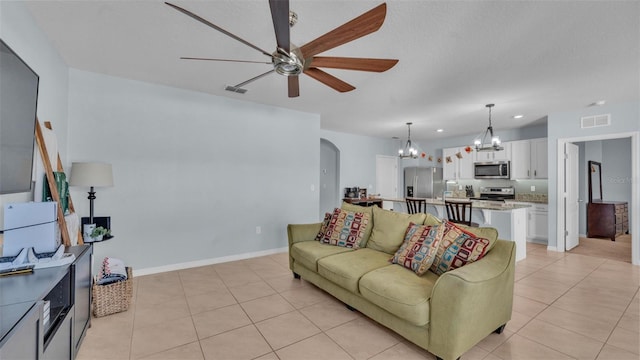 living room featuring arched walkways, light tile patterned floors, ceiling fan with notable chandelier, visible vents, and baseboards