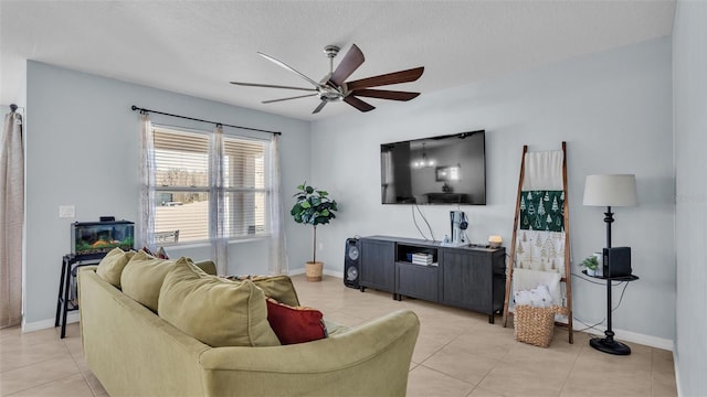 living room featuring light tile patterned floors, ceiling fan, a textured ceiling, and baseboards