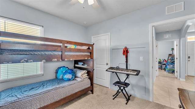 tiled bedroom with carpet, visible vents, and ceiling fan