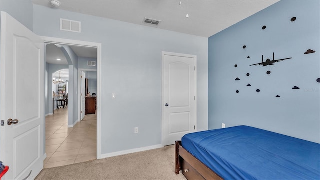 bedroom featuring arched walkways, visible vents, and light colored carpet