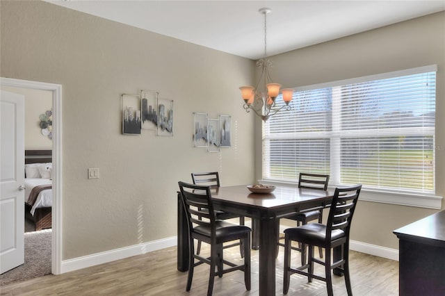 dining space featuring a notable chandelier, a healthy amount of sunlight, and light wood-type flooring