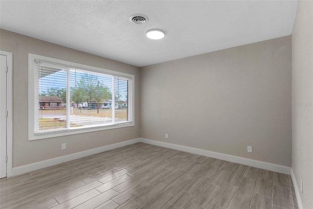 empty room with a textured ceiling and light wood-type flooring