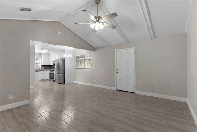 unfurnished living room with lofted ceiling with beams, ceiling fan with notable chandelier, and light hardwood / wood-style floors