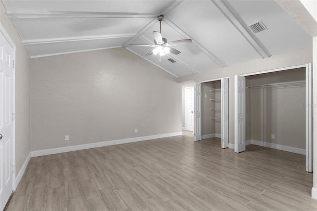 unfurnished bedroom with ceiling fan, lofted ceiling with beams, light hardwood / wood-style flooring, and two closets