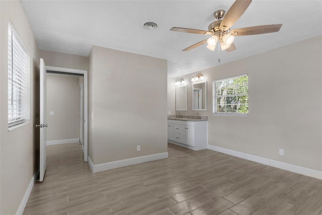 unfurnished bedroom with connected bathroom, ceiling fan, and light wood-type flooring