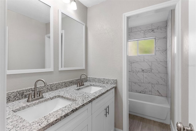 bathroom with tiled shower / bath combo, wood-type flooring, and vanity