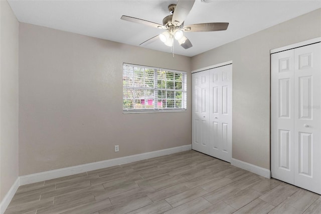 unfurnished bedroom with ceiling fan, light hardwood / wood-style floors, and two closets