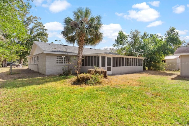 rear view of house with a sunroom and a lawn