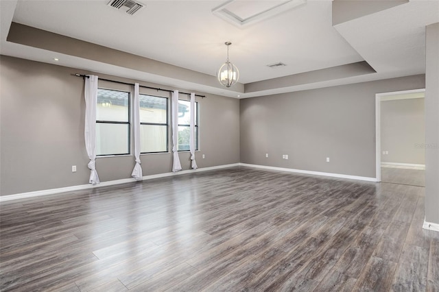 spare room with dark hardwood / wood-style floors and a raised ceiling