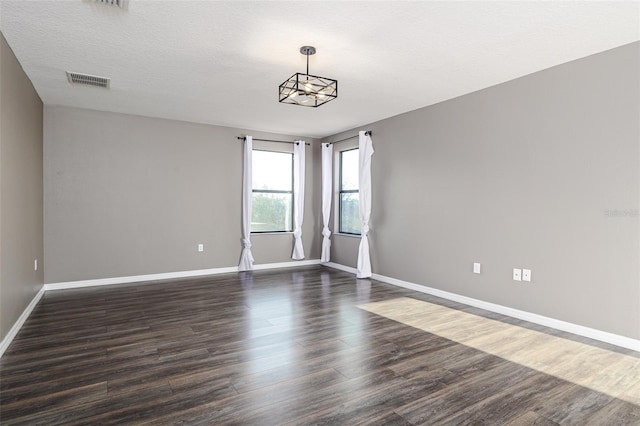 spare room featuring dark hardwood / wood-style flooring and a textured ceiling