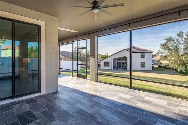 unfurnished sunroom with ceiling fan