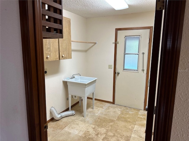 clothes washing area with cabinets, electric dryer hookup, and a textured ceiling