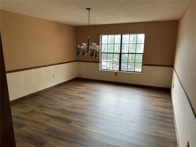 unfurnished room with a chandelier, a textured ceiling, and dark hardwood / wood-style flooring