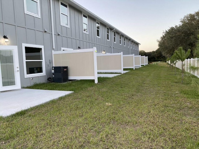 yard at dusk featuring cooling unit and a patio area