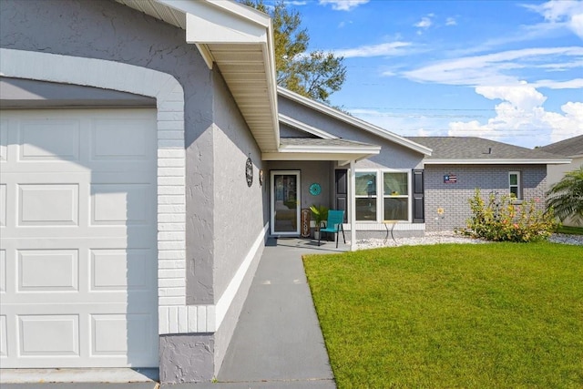 view of exterior entry with a garage and a yard