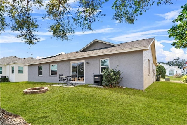 back of house featuring central AC, a lawn, a patio area, and an outdoor fire pit