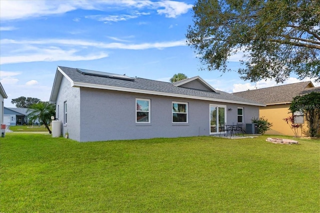 back of property featuring cooling unit, a lawn, and solar panels