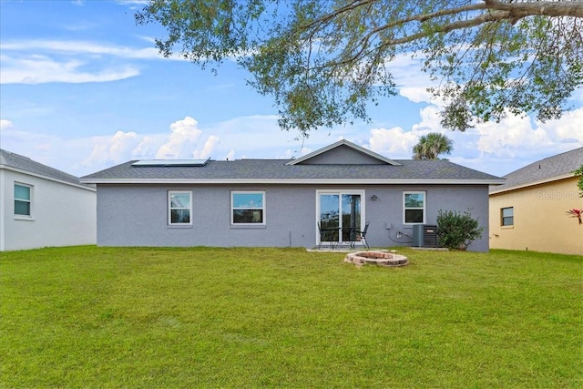 rear view of house with an outdoor fire pit, a lawn, and central air condition unit