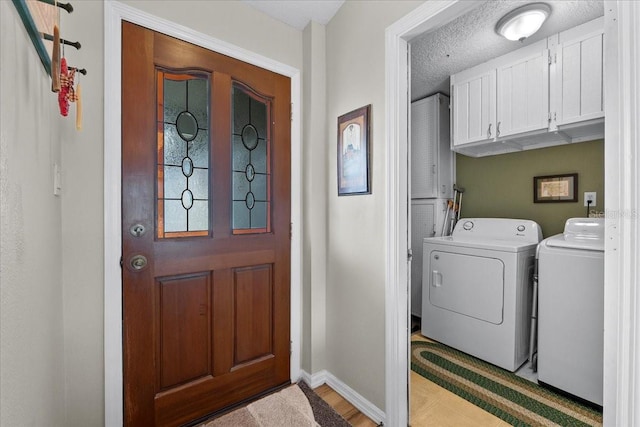 washroom featuring washer and clothes dryer, cabinets, and a textured ceiling