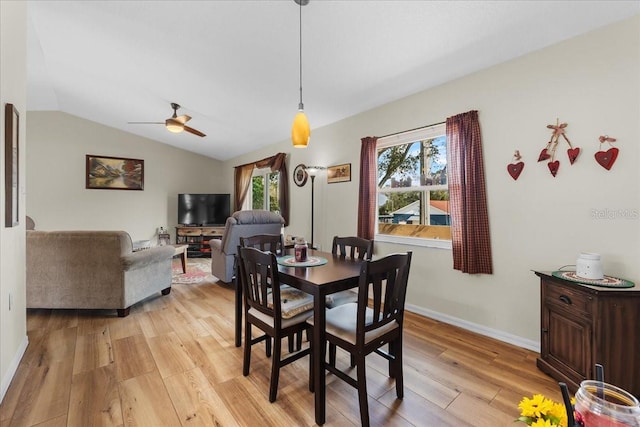 dining room featuring ceiling fan, a healthy amount of sunlight, vaulted ceiling, and light wood-type flooring