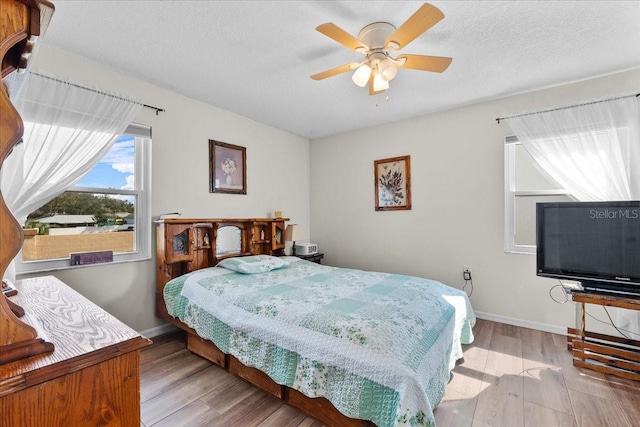 bedroom with ceiling fan, light hardwood / wood-style flooring, and a textured ceiling