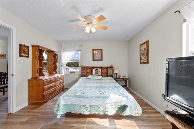 bedroom with ceiling fan, a textured ceiling, and light wood-type flooring