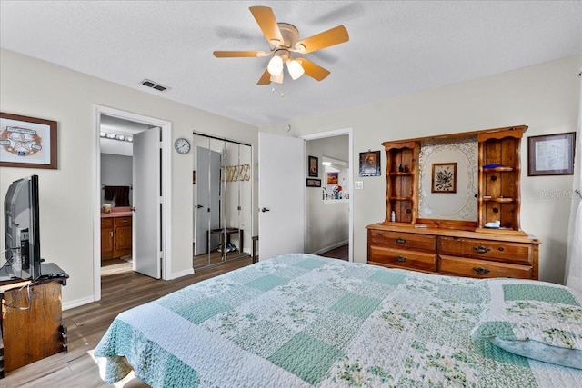 bedroom with ceiling fan, dark hardwood / wood-style floors, a textured ceiling, and ensuite bathroom