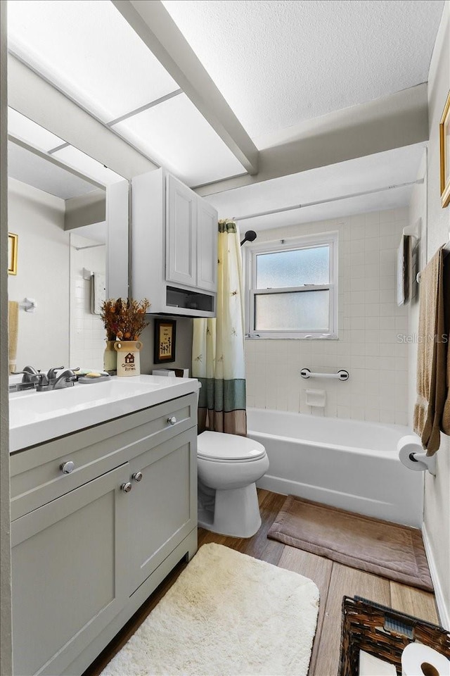 full bathroom with toilet, wood-type flooring, a textured ceiling, vanity, and shower / bathtub combination with curtain