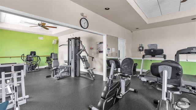 workout area featuring ceiling fan and a raised ceiling