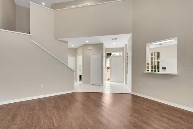 unfurnished living room with light hardwood / wood-style floors and a high ceiling