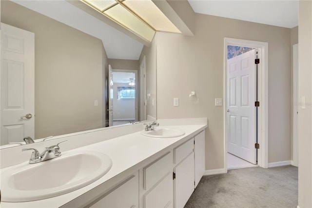 bathroom featuring double vanity, carpet floors, a sink, and baseboards