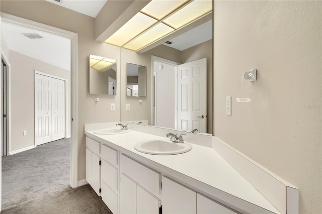 bathroom with double vanity, a sink, visible vents, and baseboards