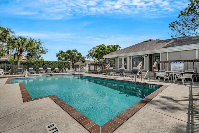 community pool with a patio area and fence