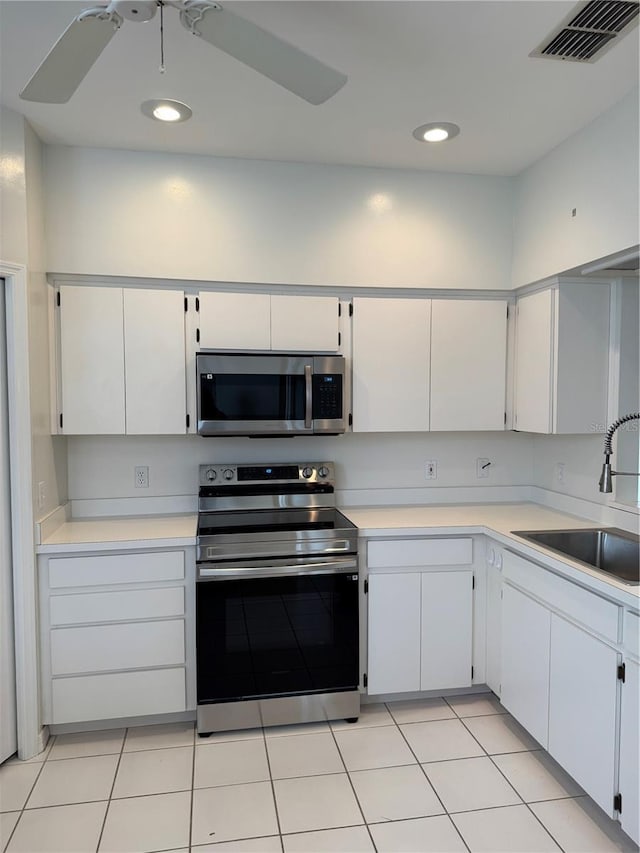 kitchen with a sink, stainless steel appliances, light countertops, and white cabinets