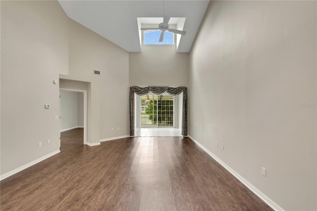 unfurnished living room featuring a high ceiling, dark wood-style flooring, visible vents, a ceiling fan, and baseboards