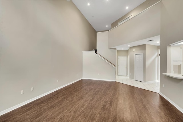 unfurnished living room featuring visible vents, baseboards, a high ceiling, light wood-type flooring, and recessed lighting