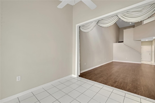 spare room with light tile patterned floors, a high ceiling, baseboards, and a ceiling fan