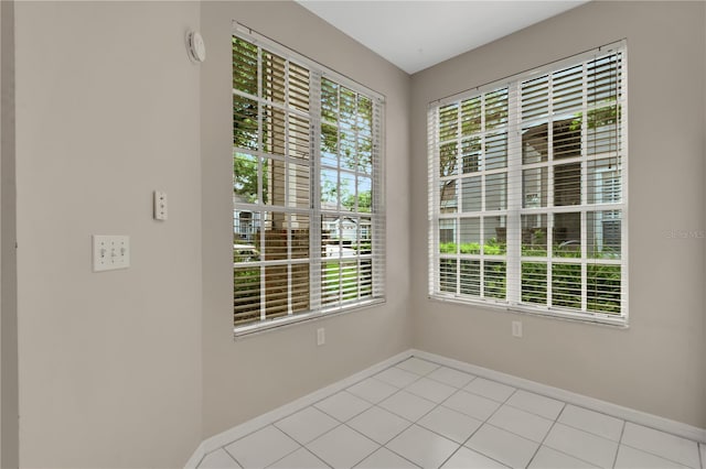 spare room with light tile patterned flooring and baseboards