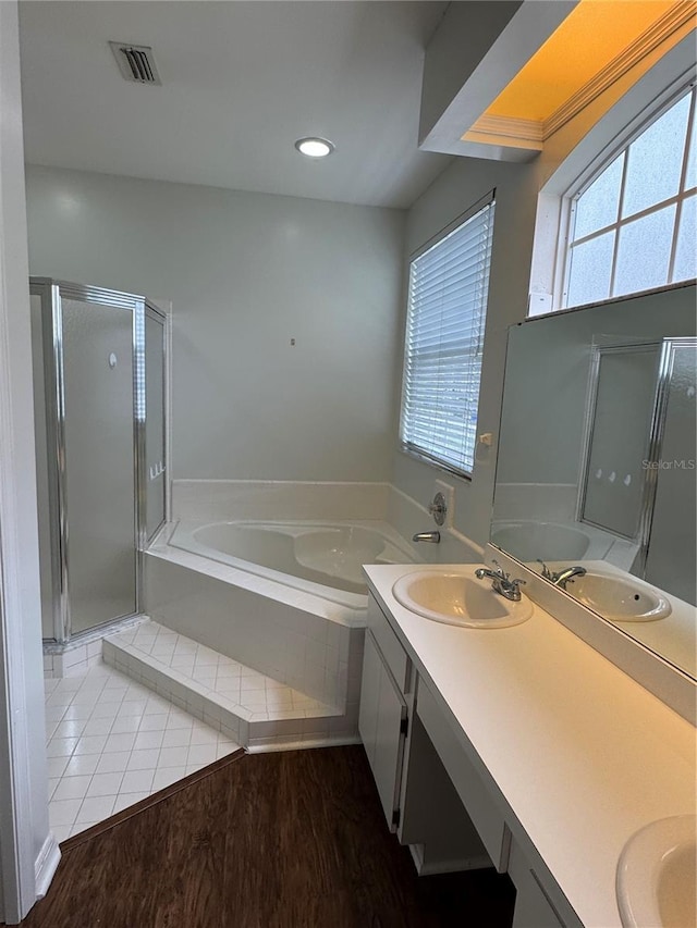 full bathroom with visible vents, a sink, a bath, and double vanity