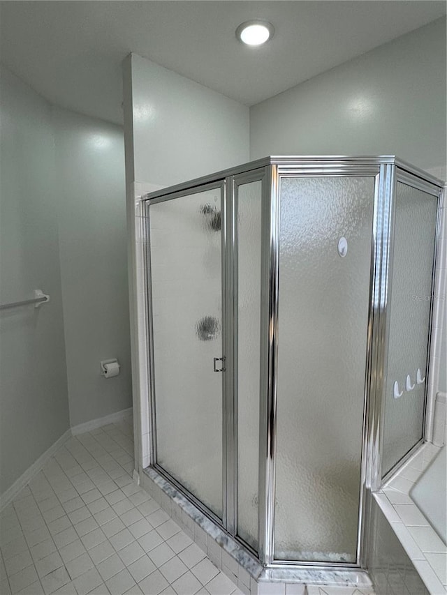 full bathroom with baseboards, a stall shower, a bath, and tile patterned floors