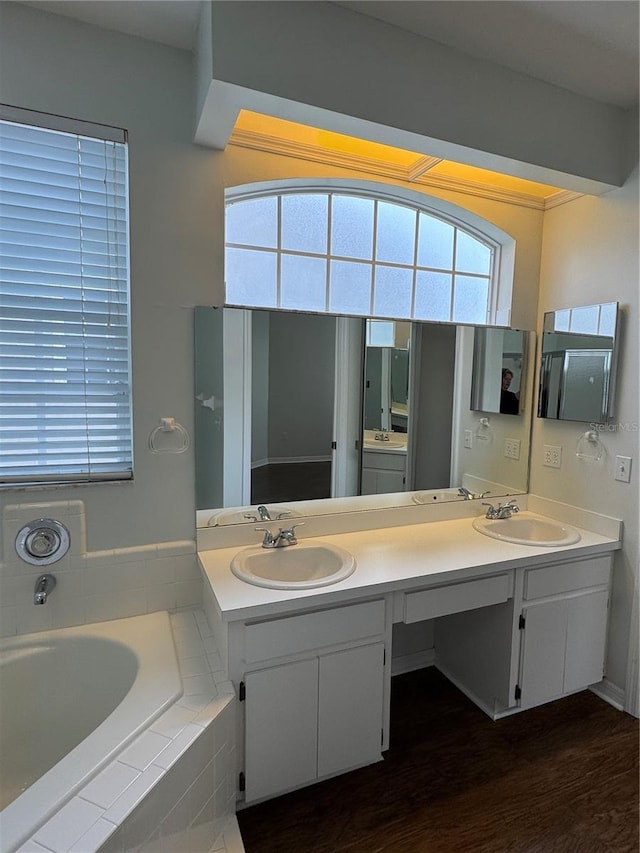 full bathroom featuring double vanity, wood finished floors, a sink, and a bath