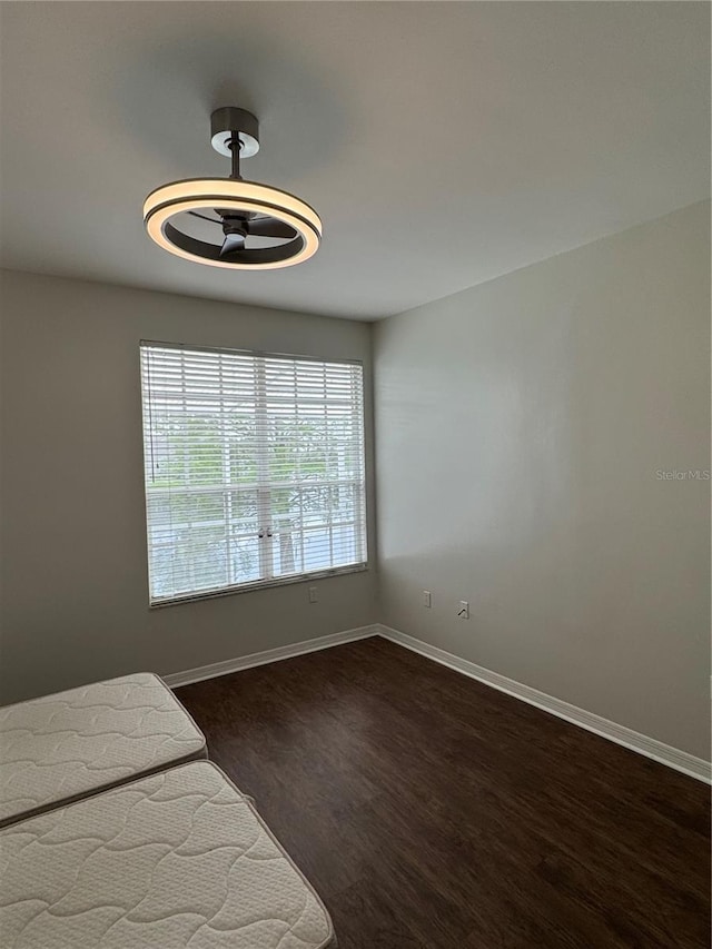 unfurnished bedroom with dark wood-type flooring and baseboards