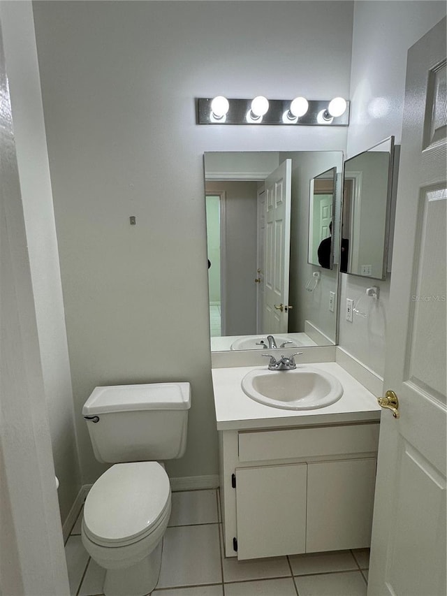 half bath with baseboards, vanity, toilet, and tile patterned floors