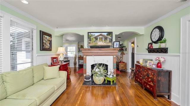 living room with hardwood / wood-style flooring, ornamental molding, and a fireplace